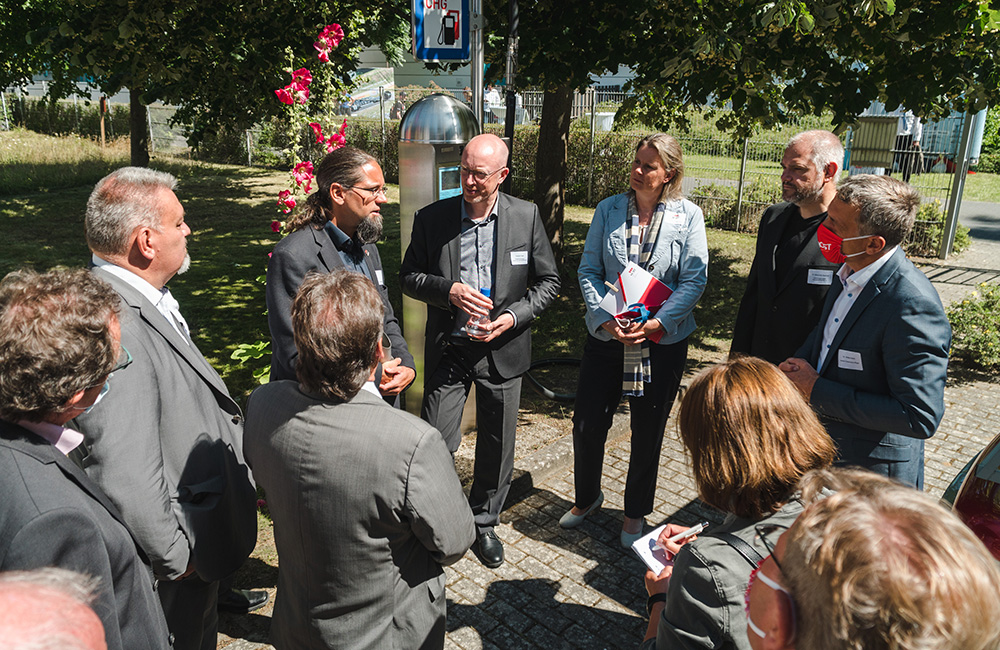 Personengruppe im Freien bei Sonnenschein die eine Pressekonferenz abhält