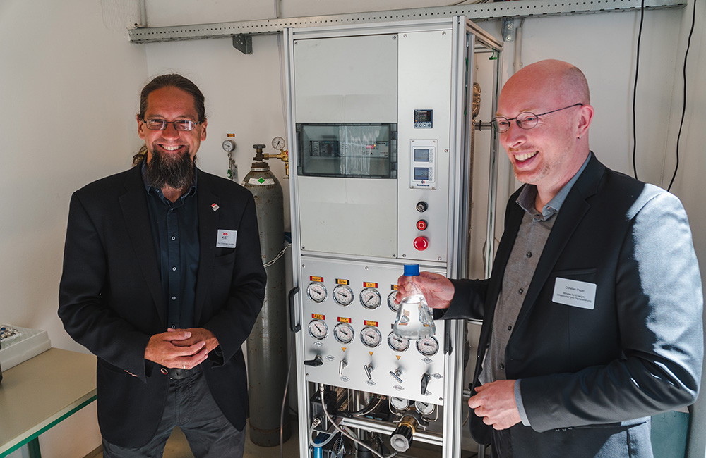 2 Personen in Anzügen vor einer Maschine zur Produktion von Methanol