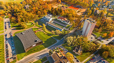 Luftaufnahme vom bewaldeten, grünen Hochschulcampus der Estonian University, mit mehreren Gebäuden und Parkplätzen