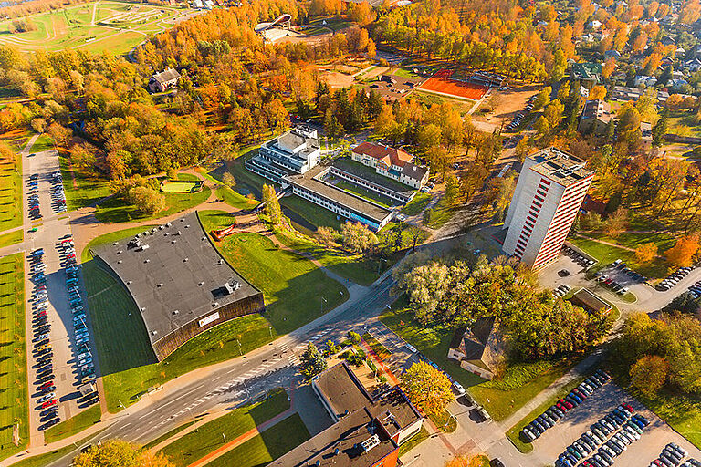 Luftaufnahme vom bewaldeten, grünen Hochschulcampus der Estonian University, mit mehreren Gebäuden und Parkplätzen
