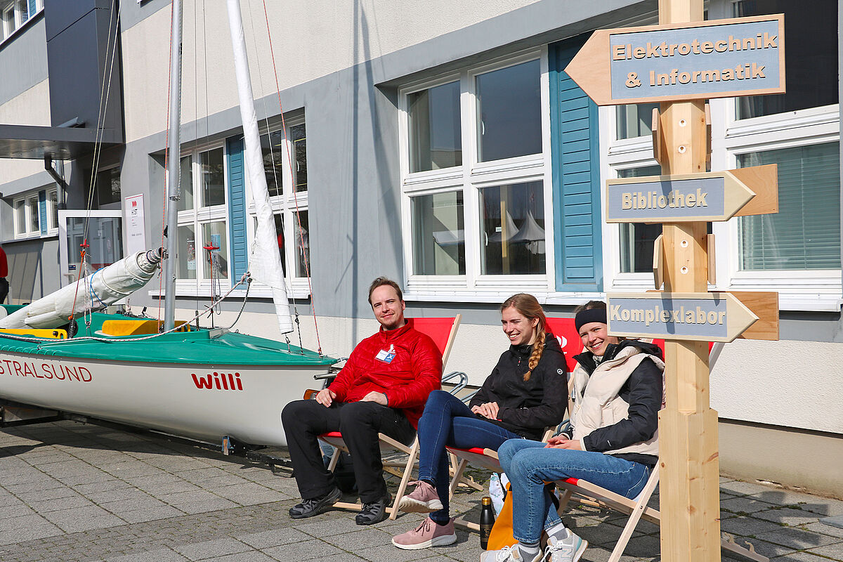 Aussteller mit einem Segelboot und den Wegweisern auf dem Campus