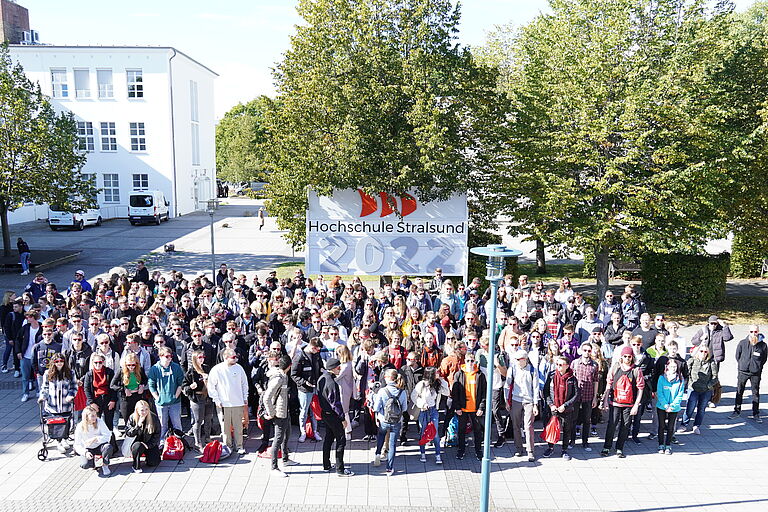 Das Bild zeigt eine sehr große Gruppe junger Menschen - die neuen Studierenden von 2022 - vor einem HOST-Schild mit der Jahreszahl 2022