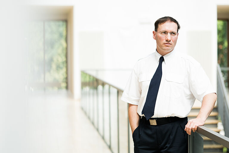 Prof. Dr.-Ing. Jens Ladisch, mit weißem Hemd und Krawatte an einem Geländer