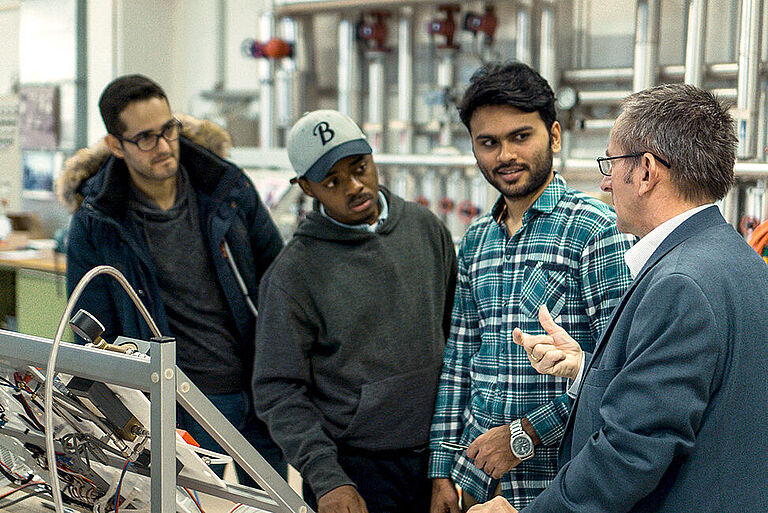Prof. Thomas Luschtinetz im Gespräch mit 3 internationalen Studierenden im Labor