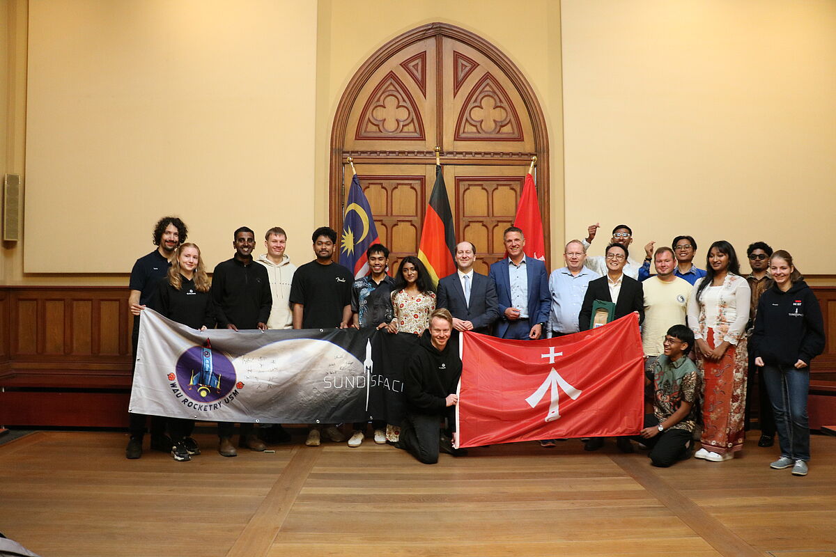 Gruppenfoto mit allen Beteiligten. Sie halten jeweils ihre Flagge.