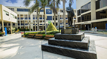Die Statue eines Mannes vor einem Universitätsgebäude.