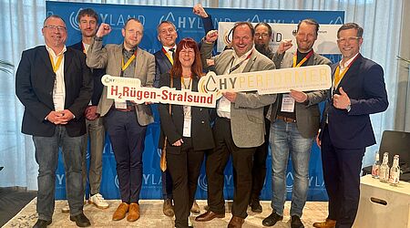 Eine Gruppe von neun Menschen hält Schilder, die die Region Rügen Stralsund als HyPerformer ausweisen.