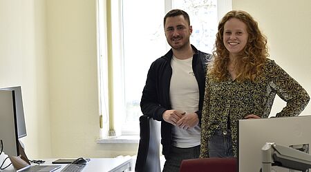 Anna Elisa Völz und Johannes Mai von NOX AAL Technologies stehen in einem Büro, sie vorn, er knapp dahinter, beide lächeln in die Kamera.