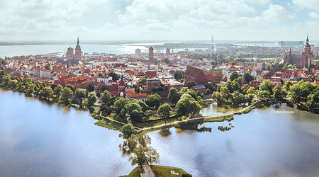 Blick auf die Altstadt der Hansestadt Stralsund von oben - mit viel Wasser und vor blauem Himmel mit weißen Wolken