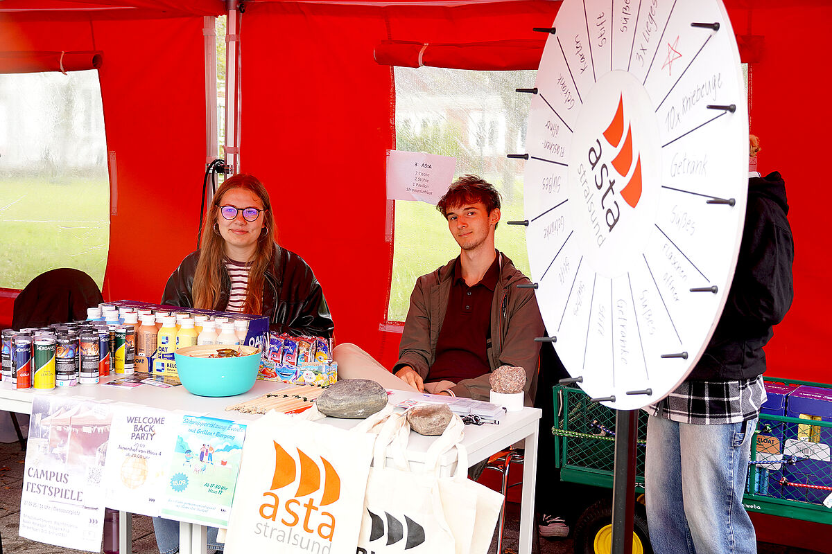 Der Asta auf der Hochschulmesse mit Glücksrad und zwei Mitgliedern