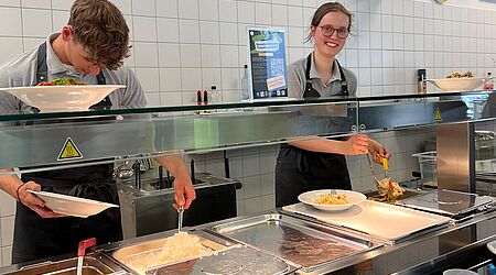 2 Studierende stehen hinter dem Mensa-Tresen