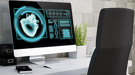 Computergeneriertes Bild mit eim Bürotisch und -stuhl. Auf dem Computer ist ein symbolischen Herz und ein DNS-Strang abgebildet.
