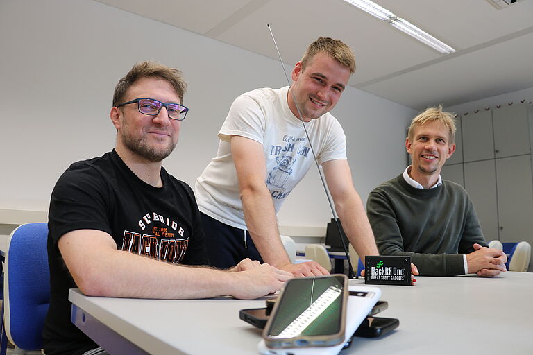 Drei Männer, die freundlich in die Kamera schauen, Handys vor sich auf dem Tisch: Prof. Dr. Andreas Noack, Justin Schnurbusch als wissenschaftliche Hilfskraft im Projekt und Prof. Dr. Jan Sölter