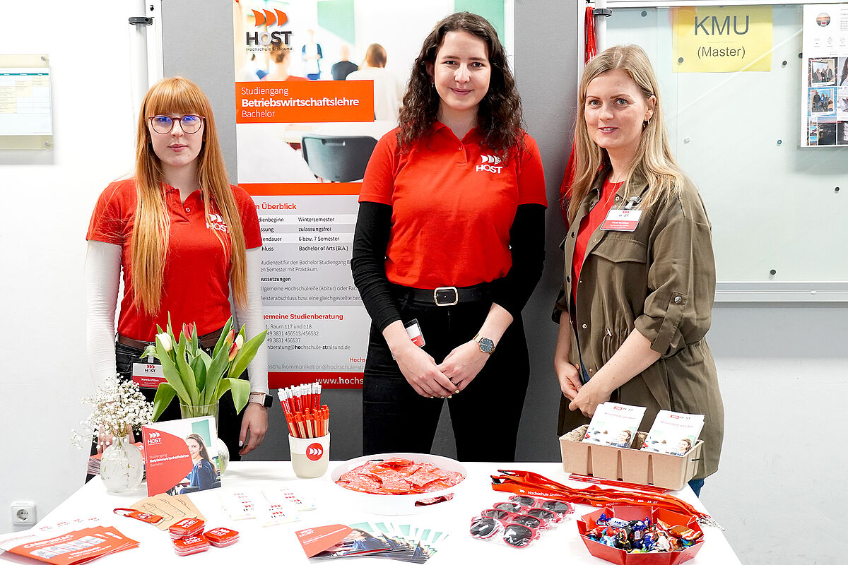 Drei Frauen stehen vor dem Stand für den Studiengang BWL