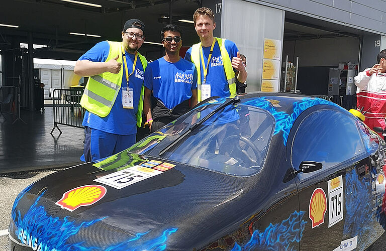 drei team-Mitglieder vor dem Bengalo, einem runderen Rennwagen, stehend