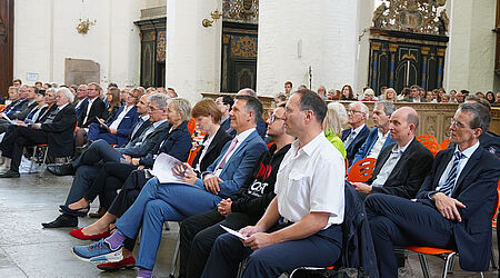 Mehrere Menschen sitzen in Reihe in einer Kirche