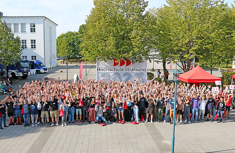Gruppenbild der vielen neuen Studierenden, die im Herbst 2023 angefangen haben an der HOST zu studieren, vor einem großen HOST-Schild.