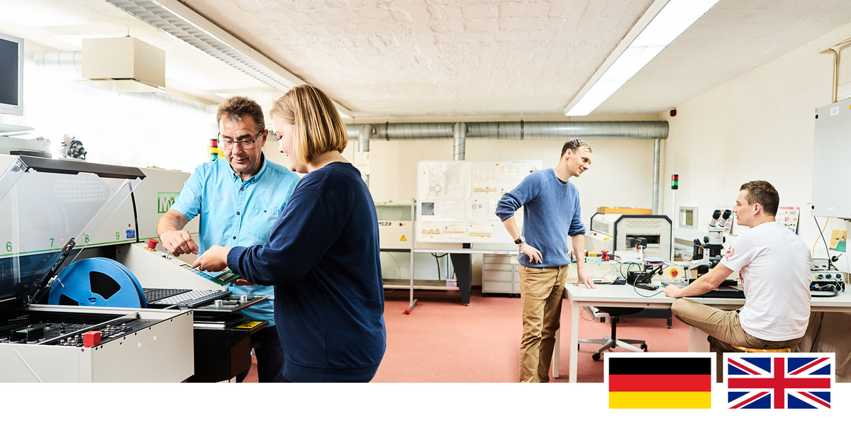 Headerfoto: Studierende und Professoren an elektrischen Maschinen im Labor