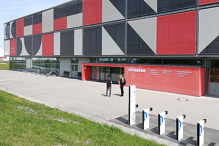 blockförmiges Gebäude der überdachter Eingangsbereich eines Campusgebäudes der University of West Bohemia mit großflächigen Farbonermenten in rot, grau und schwarz