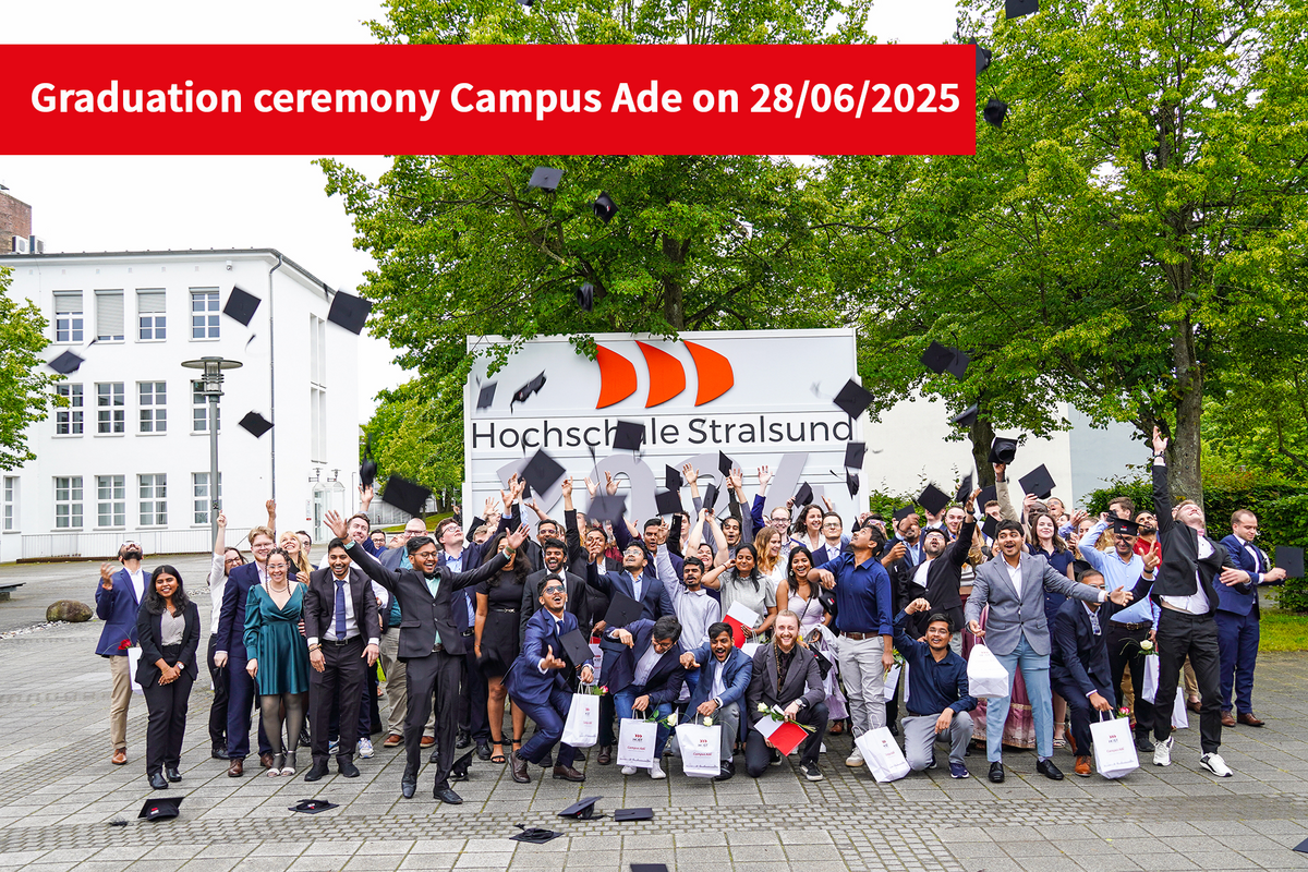 Our graduates throw their graduation caps in the air in front of a large wooden sign with the year