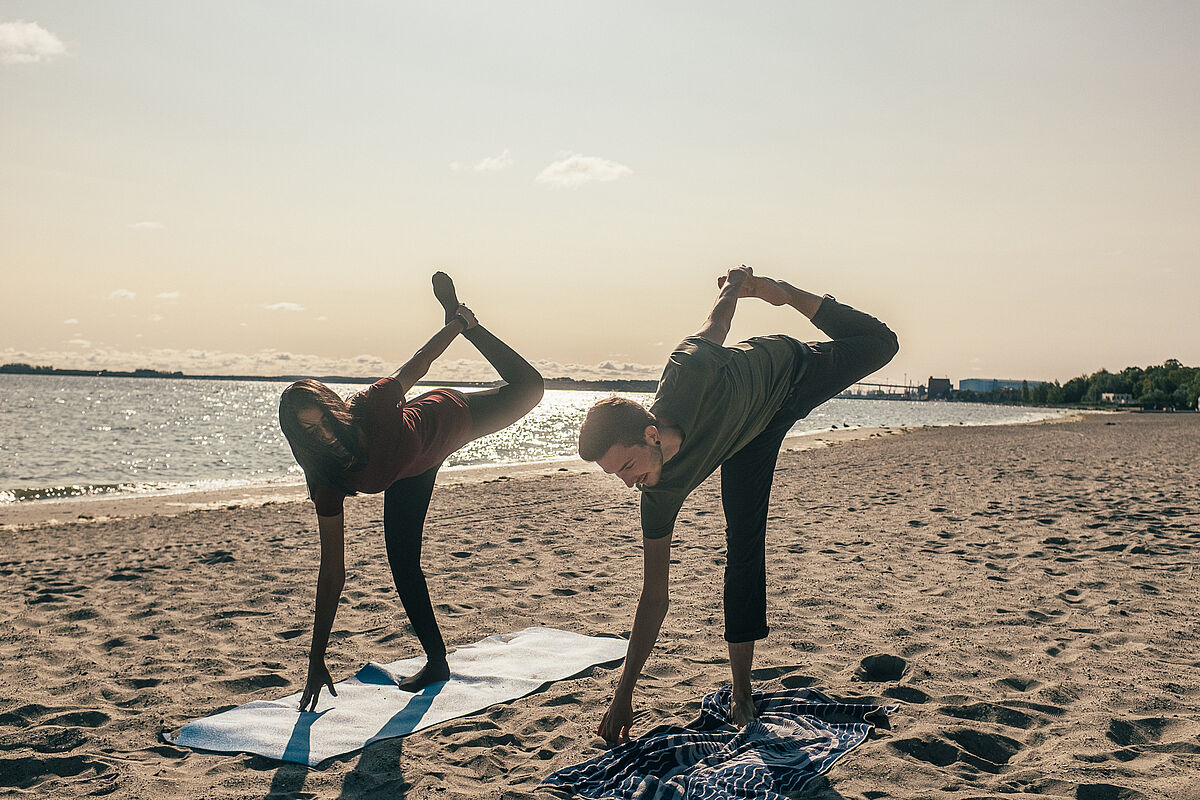 Two people doing yoga on the beach