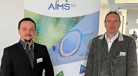 Zwei Männer (Arnold Lange und Prof. Dr. Mark Vehse) stehen vor dem Roll-up-Plakat des Projektes Aim 5.0