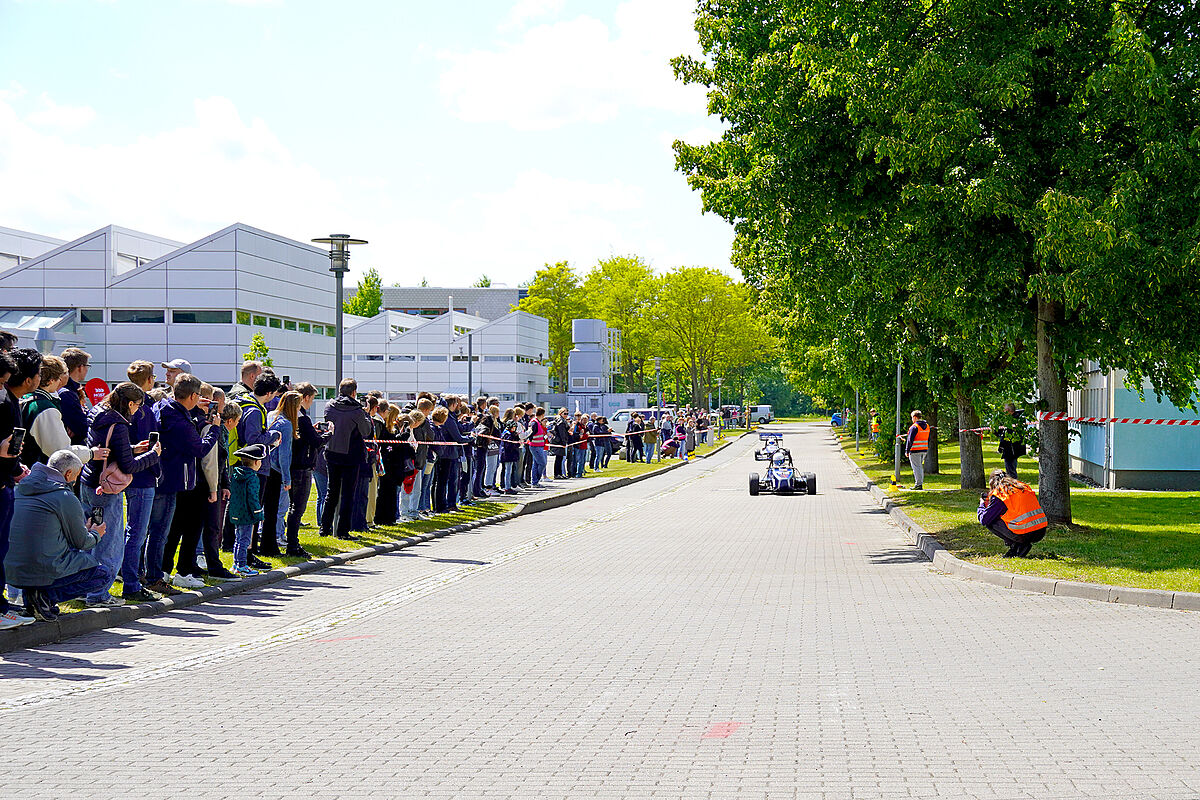 Zwei Fahrzeuge vom Baltic Racing Team bei der Showfahrt. Besucher sind im Hintergrund hinter der Absperrung.