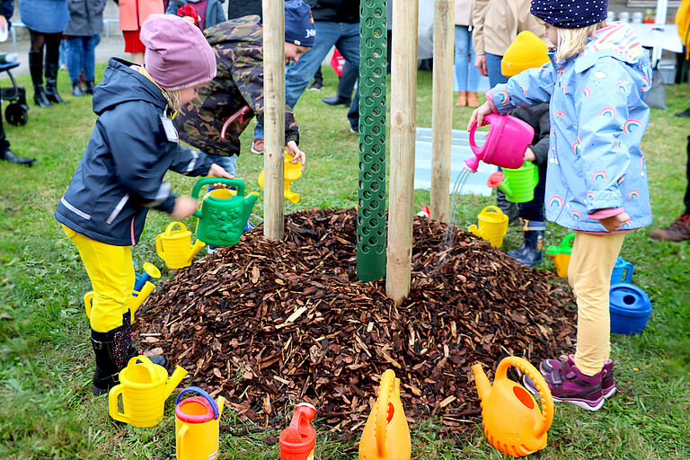 Kinder gießen den Baum beim Kinder- und Bäumchenfest