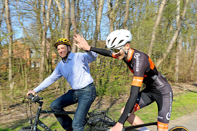 Zwei Männer beim Fahrradfahren und sich abklatschen.