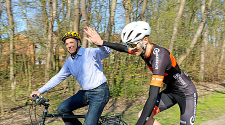 Zwei Männer beim Fahrradfahren und sich abklatschen.