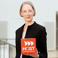 Das Portrait der Professorin Katja Matthias mit einem Würfel mit dem HOST-Logo
